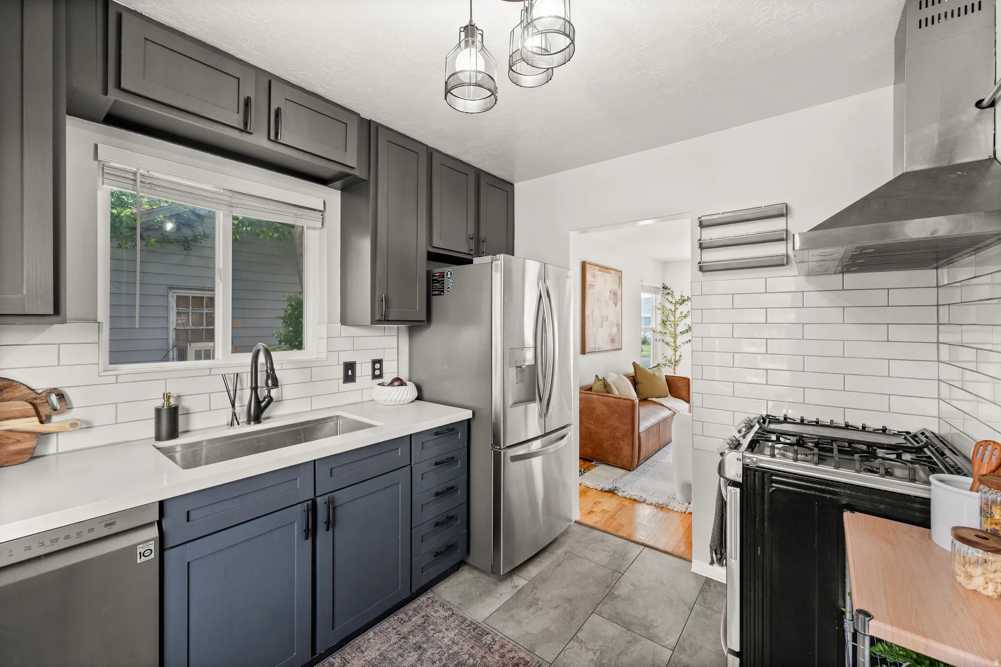 Kitchen featuring dual-toned cabinetry, stainless steel appliances, a white subway tile backsplash, and light-colored countertops
