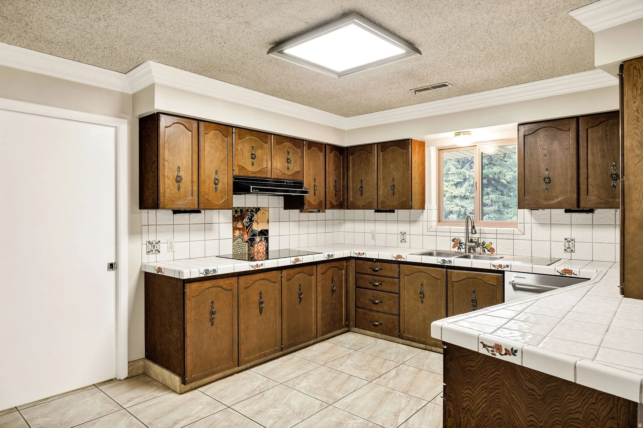 Kitchen featuring extensive wood cabinetry, tile countertops, and a tile backsplash