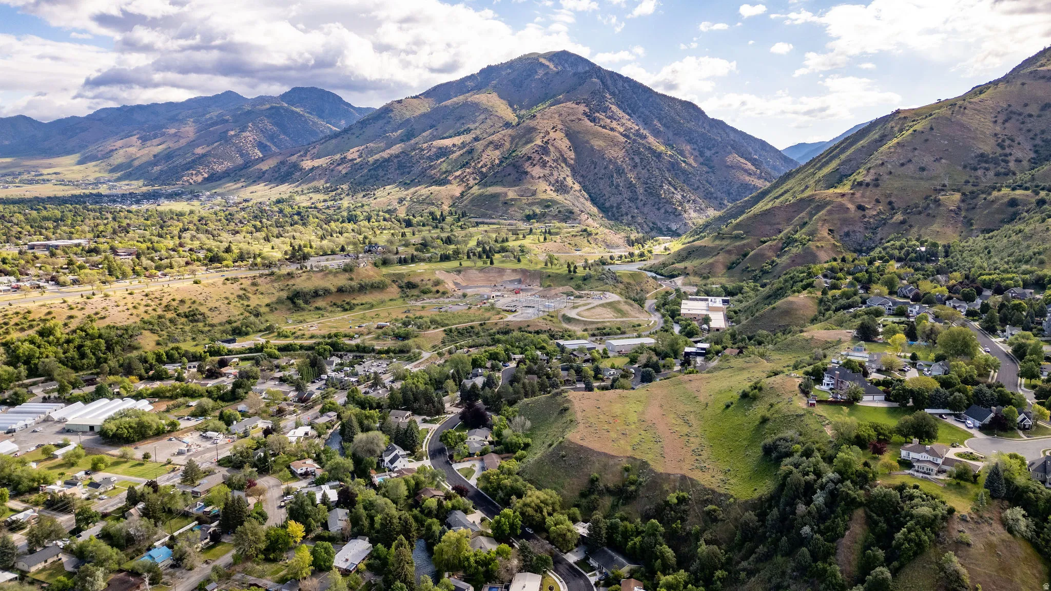 Mountainous landscape featuring a residential area with varied rooflines and surrounding green spaces
