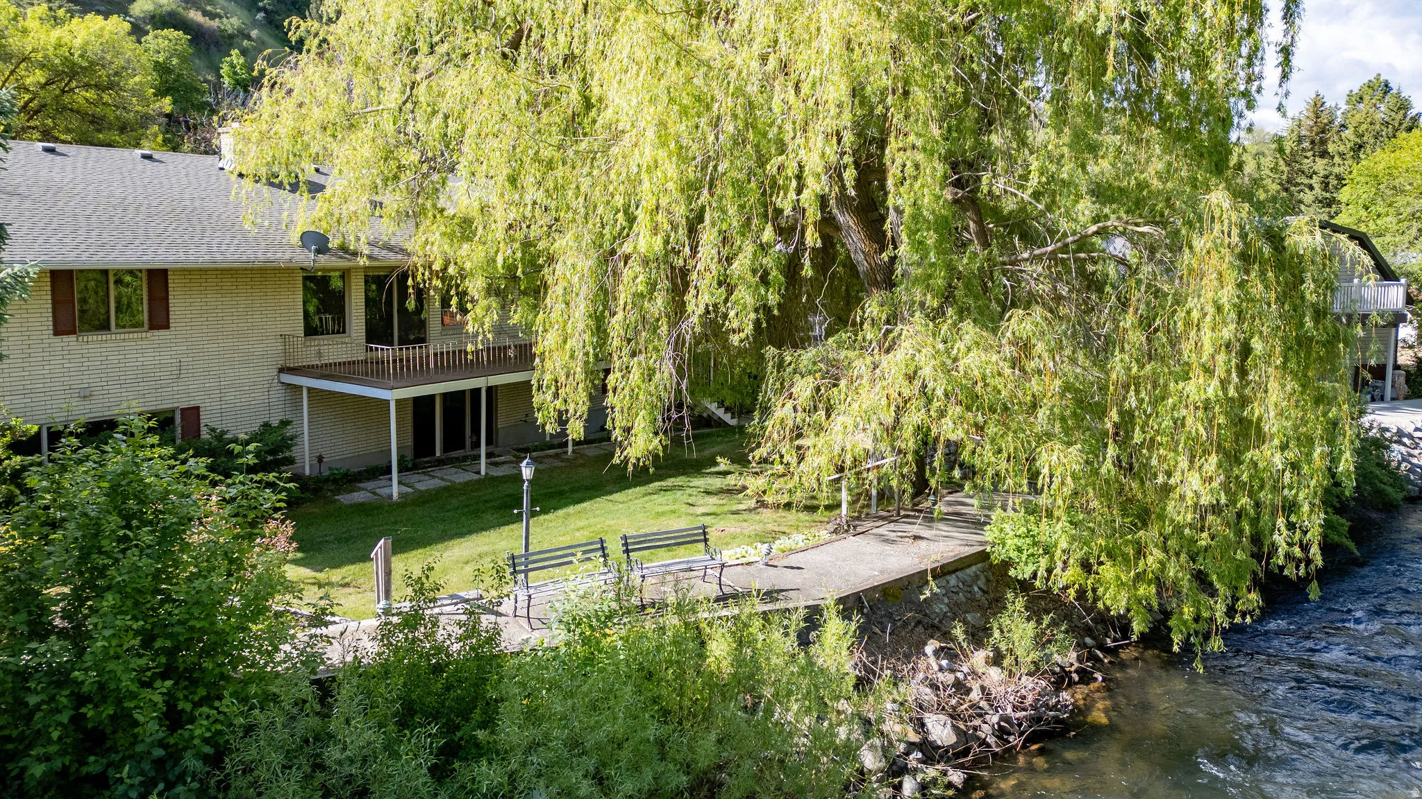 Expansive green lawn with mature weeping willow tree