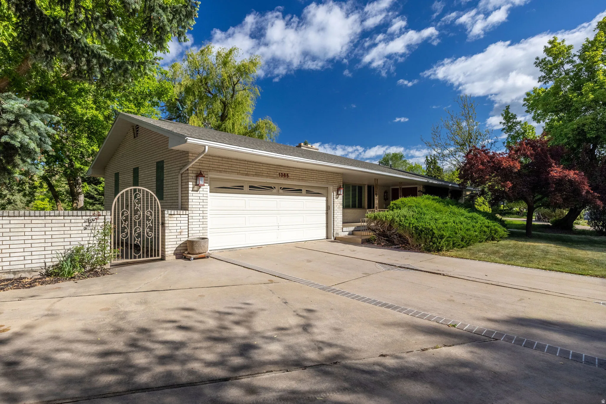 Single-story residence featuring light-colored brick exterior, attached two-car garage, and a concrete driveway