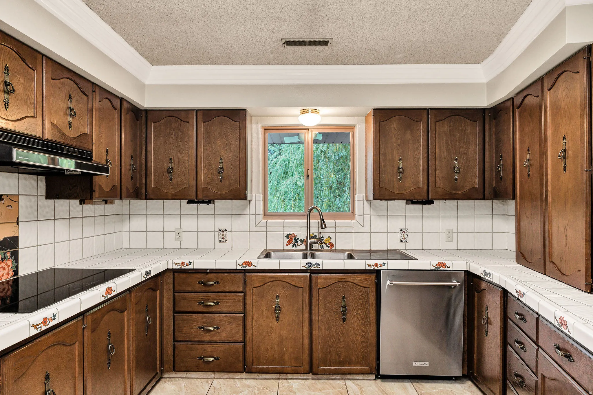 U-shaped kitchen featuring wood cabinetry, white tiled countertops, white square tile backsplash, and a stainless steel dishwasher