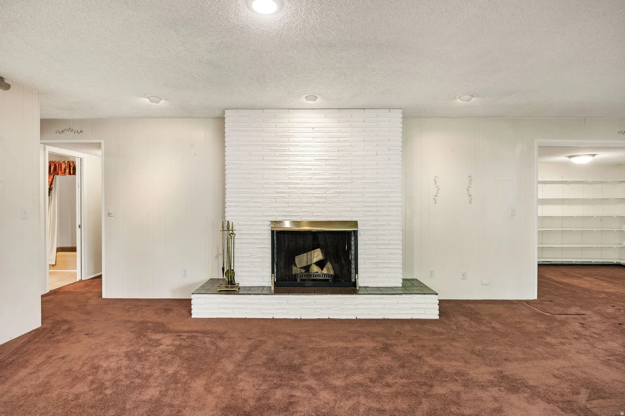 Living area featuring a painted brick fireplace with a brass surround and a tiled hearth