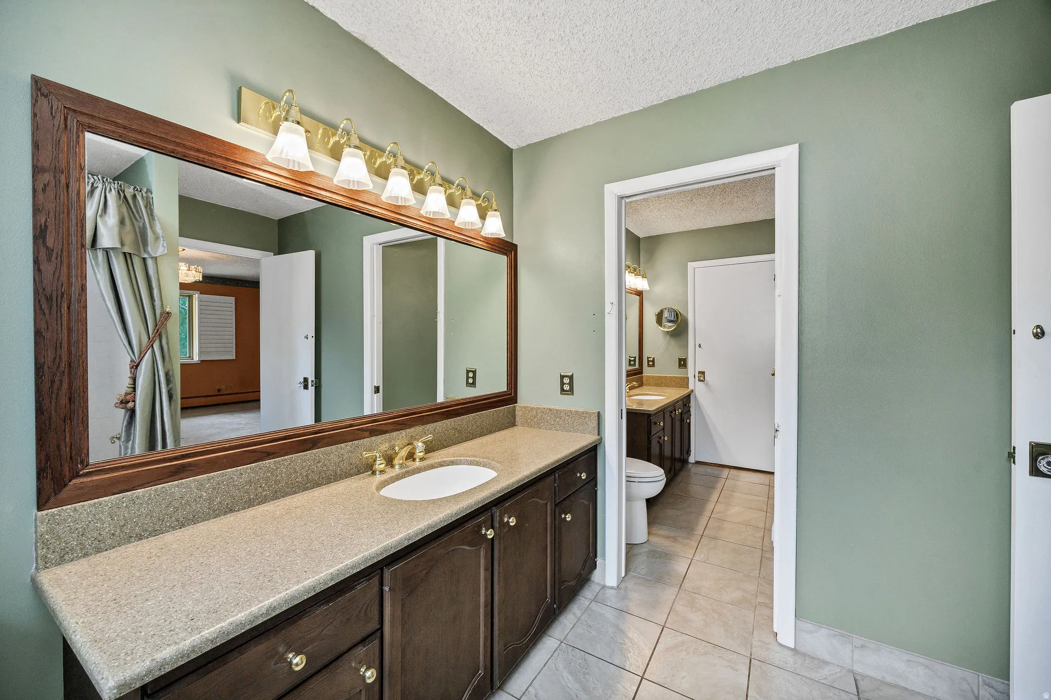 Bathroom vanity featuring a single sink, gold-finish faucet, and a speckled countertop