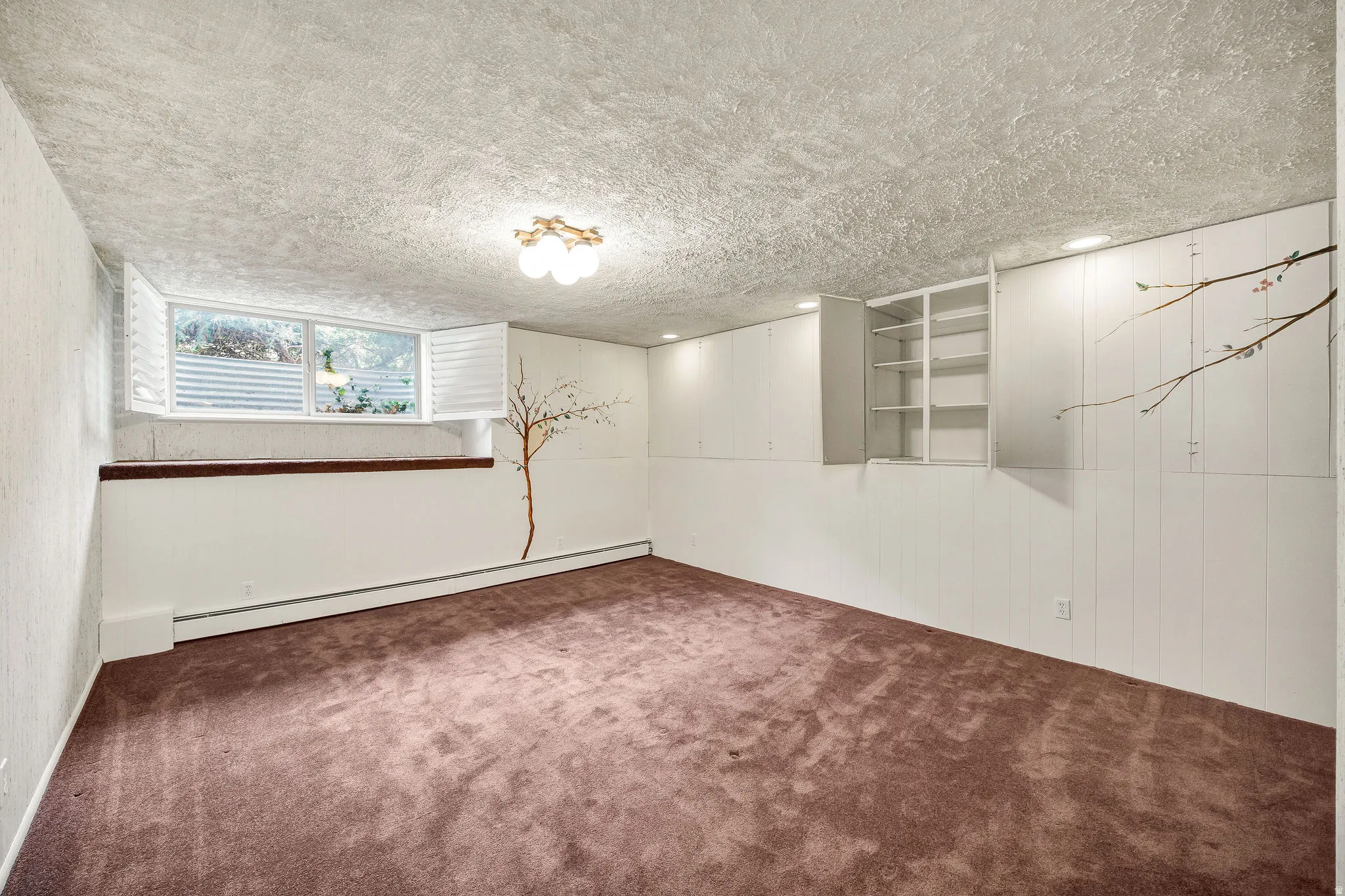 Spacious room featuring carpeting, a multi-pane window with plantation shutters, built-in shelving, and recessed lighting, with additional flush-mount lighting