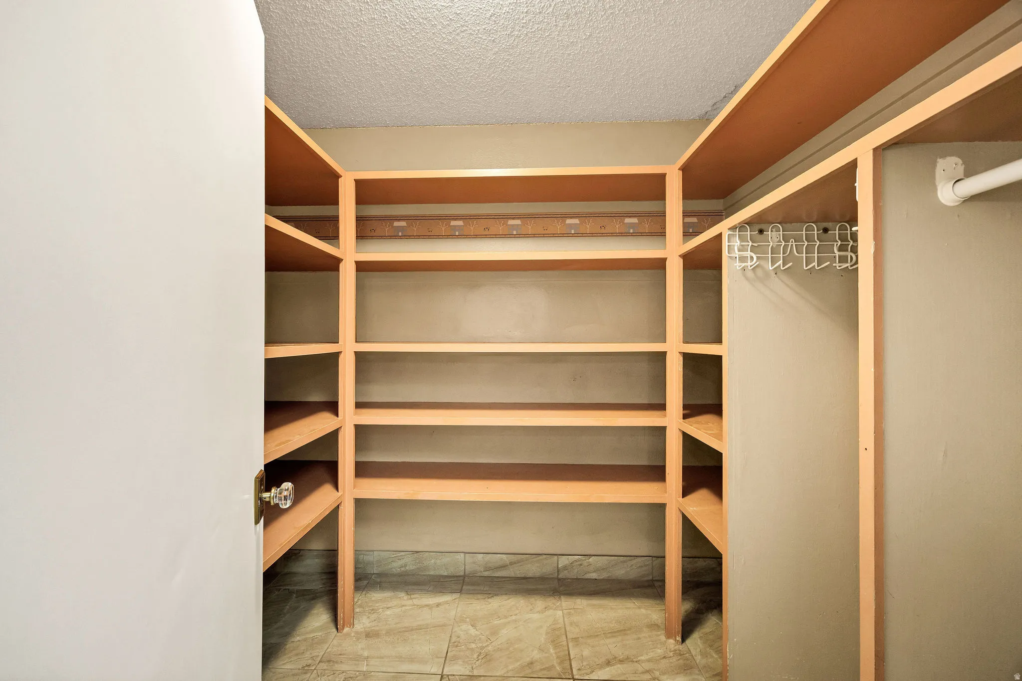 Walk-in closet featuring extensive built-in shelving, a hanging rod, light-colored walls, and tiled flooring