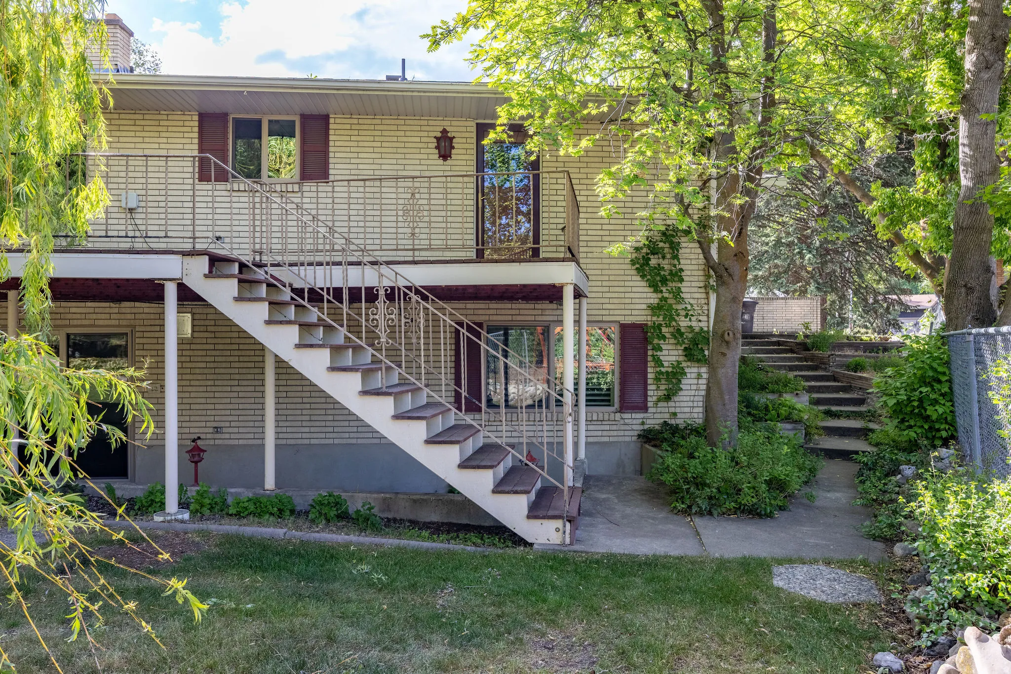 Rear exterior featuring light-colored brick siding and a white metal railing system