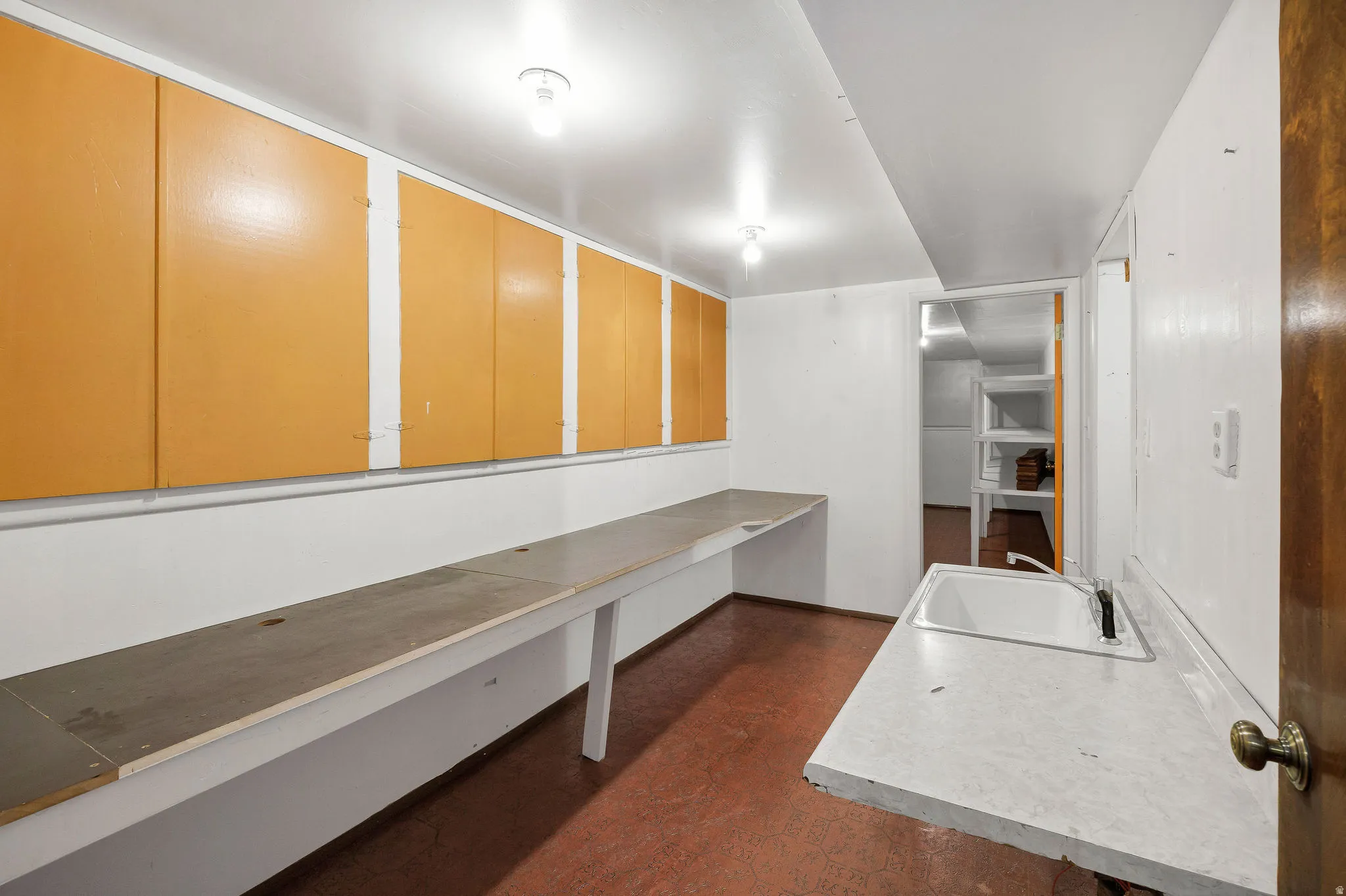 Utility room featuring extensive built-in cabinetry, long countertops, and a white single-basin sink with a faucet