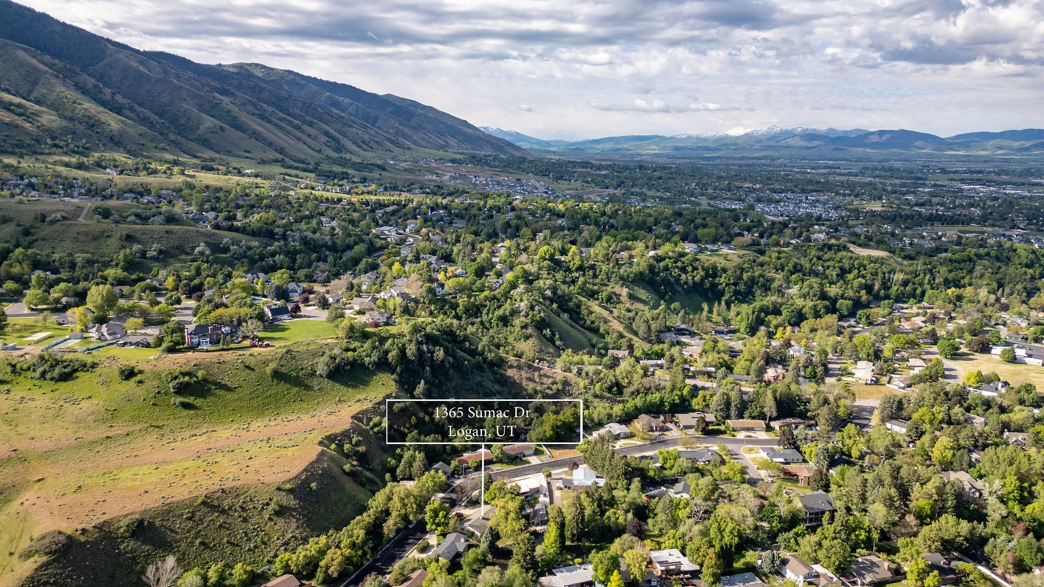 Aerial perspective showcasing a residential area amidst a mountainous landscape with distant snow-capped peaks