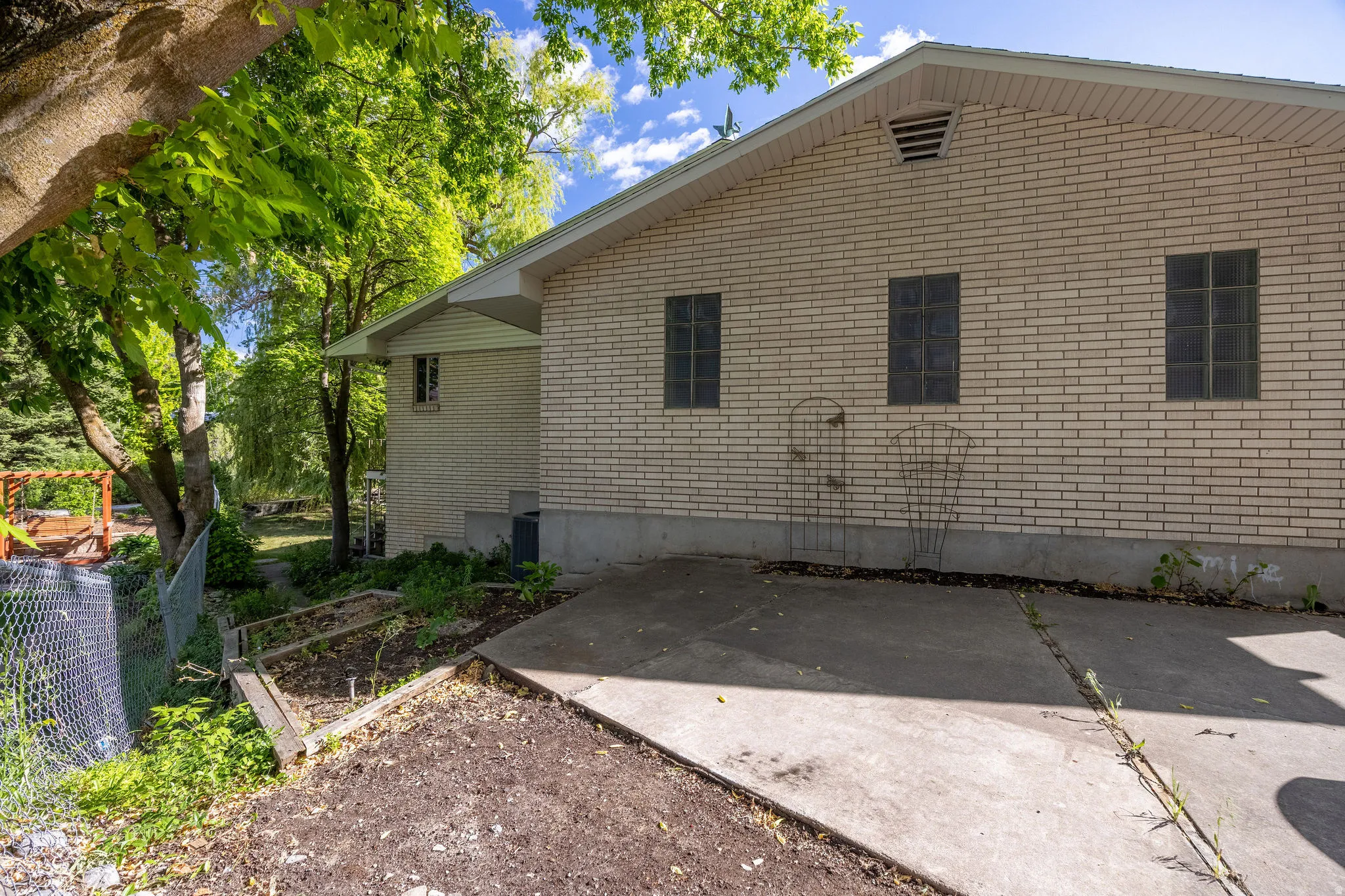 Light-colored brick exterior with three rectangular windows and a concrete driveway