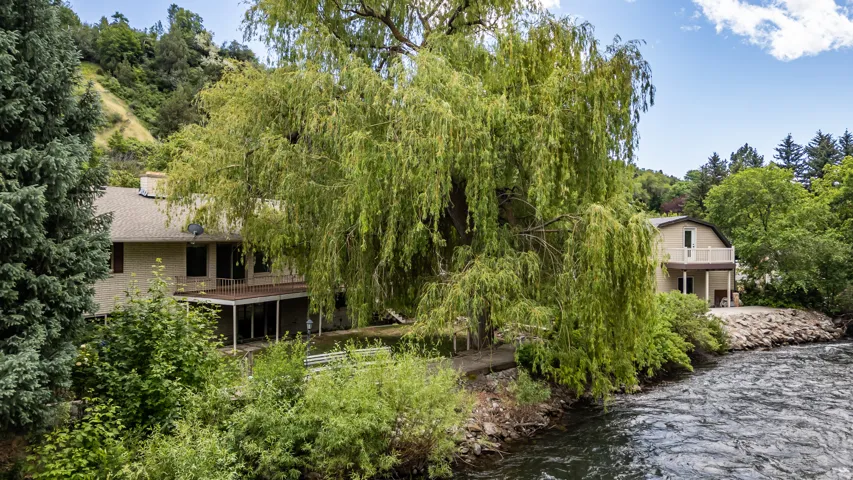 Riverside property featuring a multi-level house with a covered lower deck and an upper-level balcony