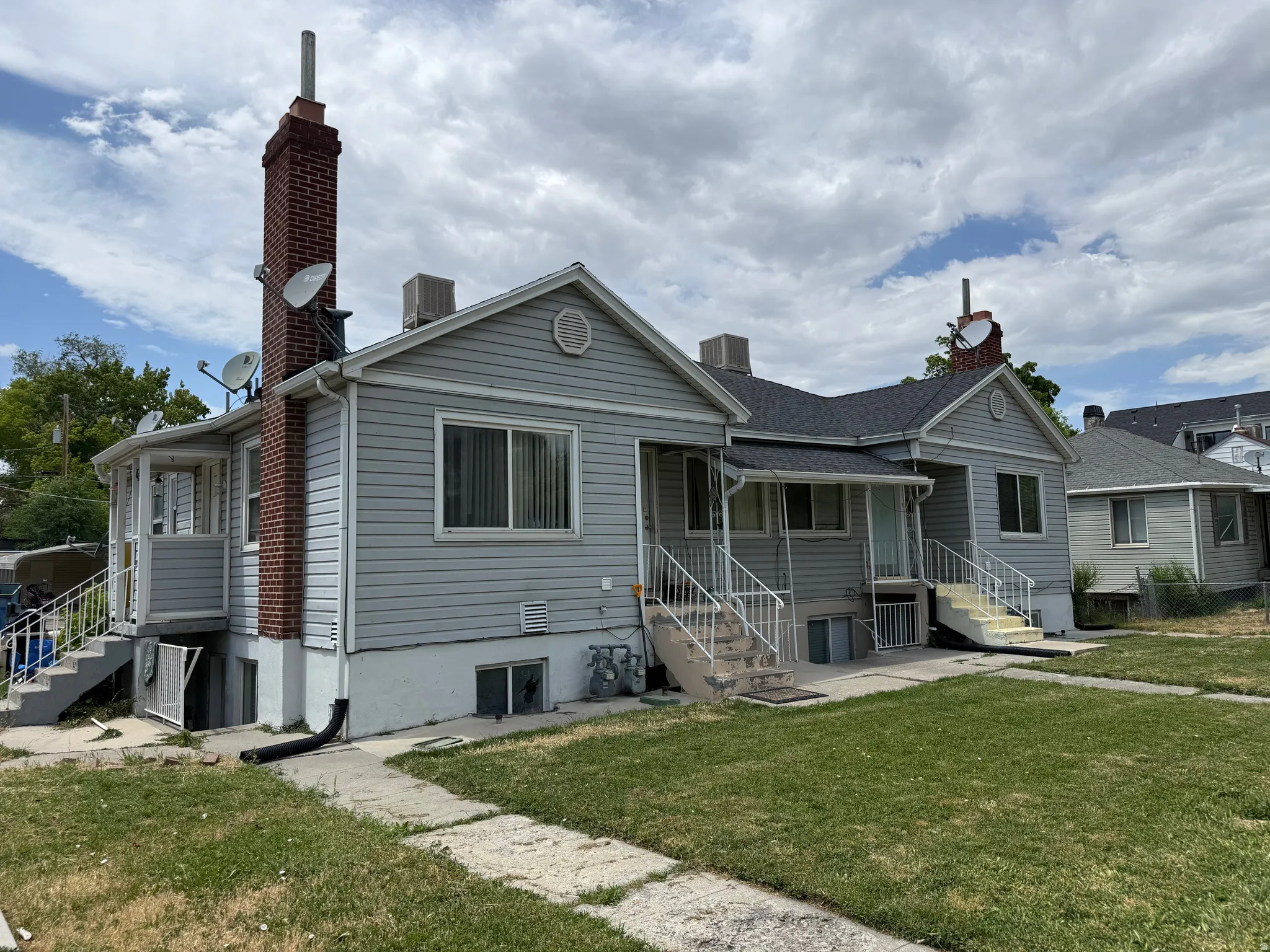 Exterior featuring light gray siding, a dark gray shingle roof, and multiple entryways with white railings