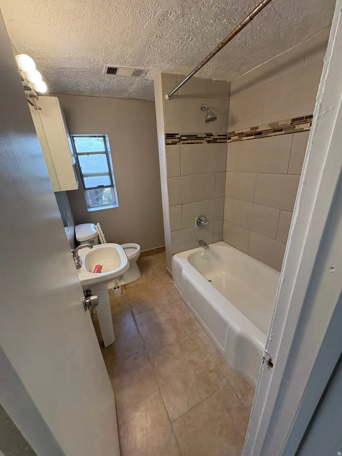 Bathroom featuring a pedestal sink, a toilet, and a bathtub with a shower