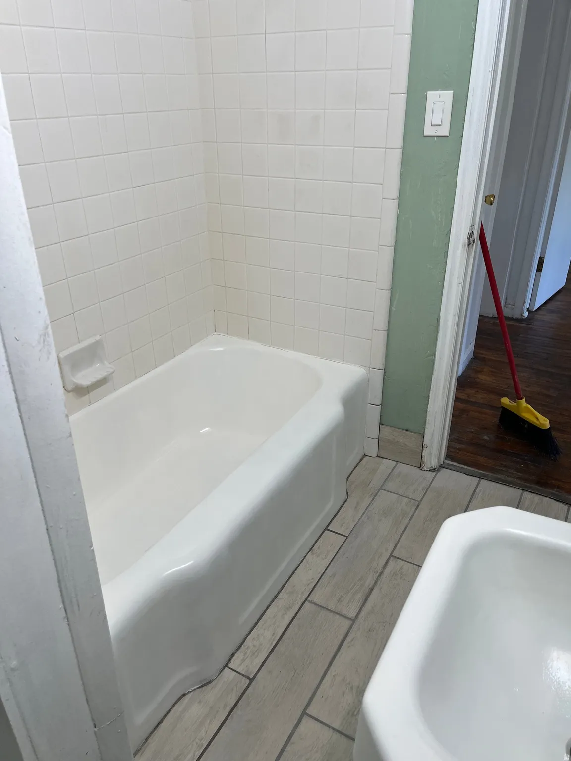 White tiled shower surround with a porcelain bathtub