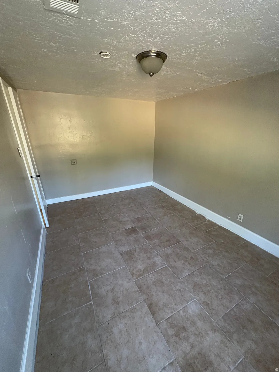 Neutral-toned ceramic tile flooring extending throughout the space, complemented by light-colored walls and white baseboards