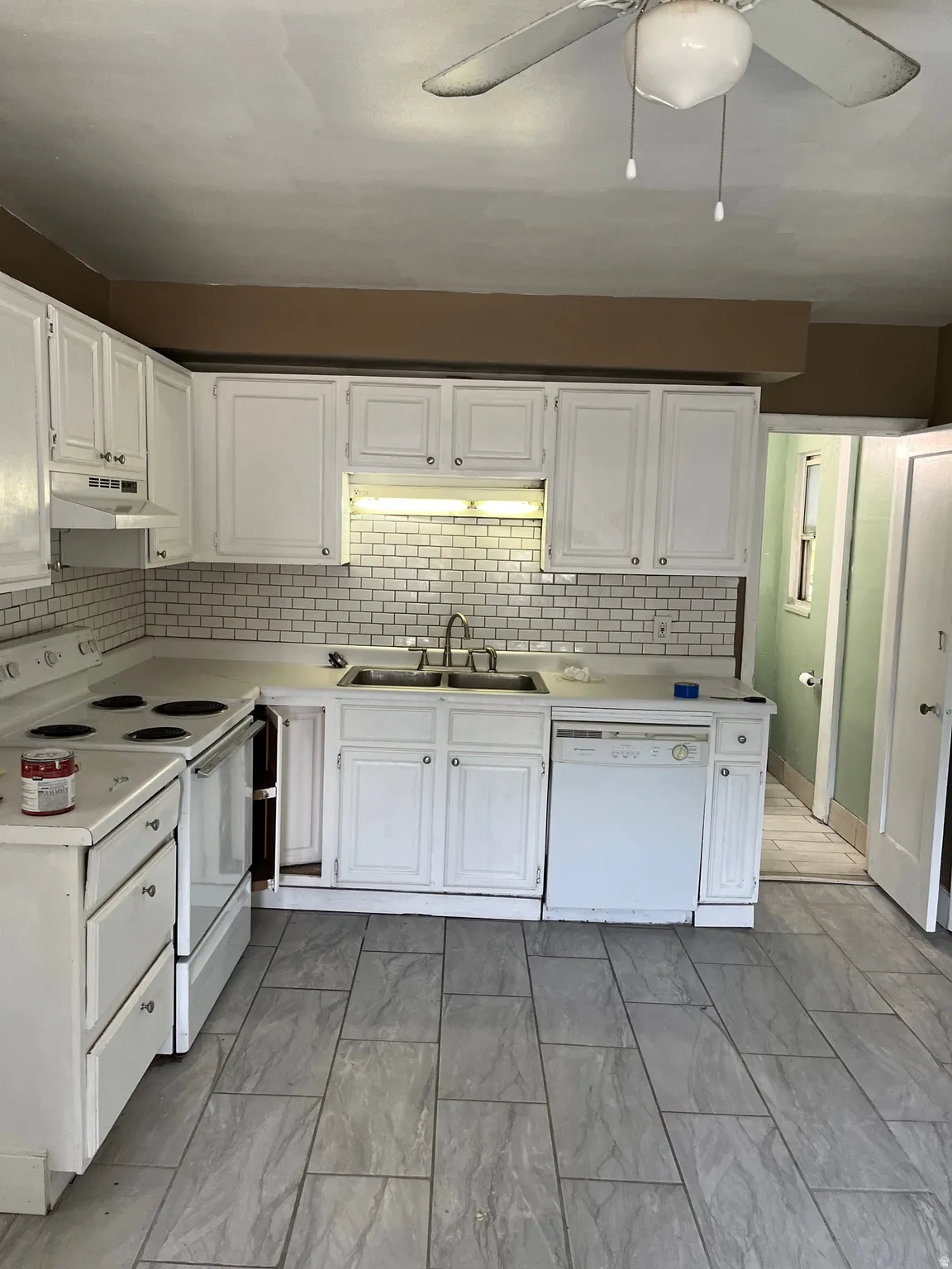 Kitchen featuring white cabinetry with brushed nickel hardware, a subway tile backsplash, a double basin stainless steel sink, and a matching white electric range and dishwasher