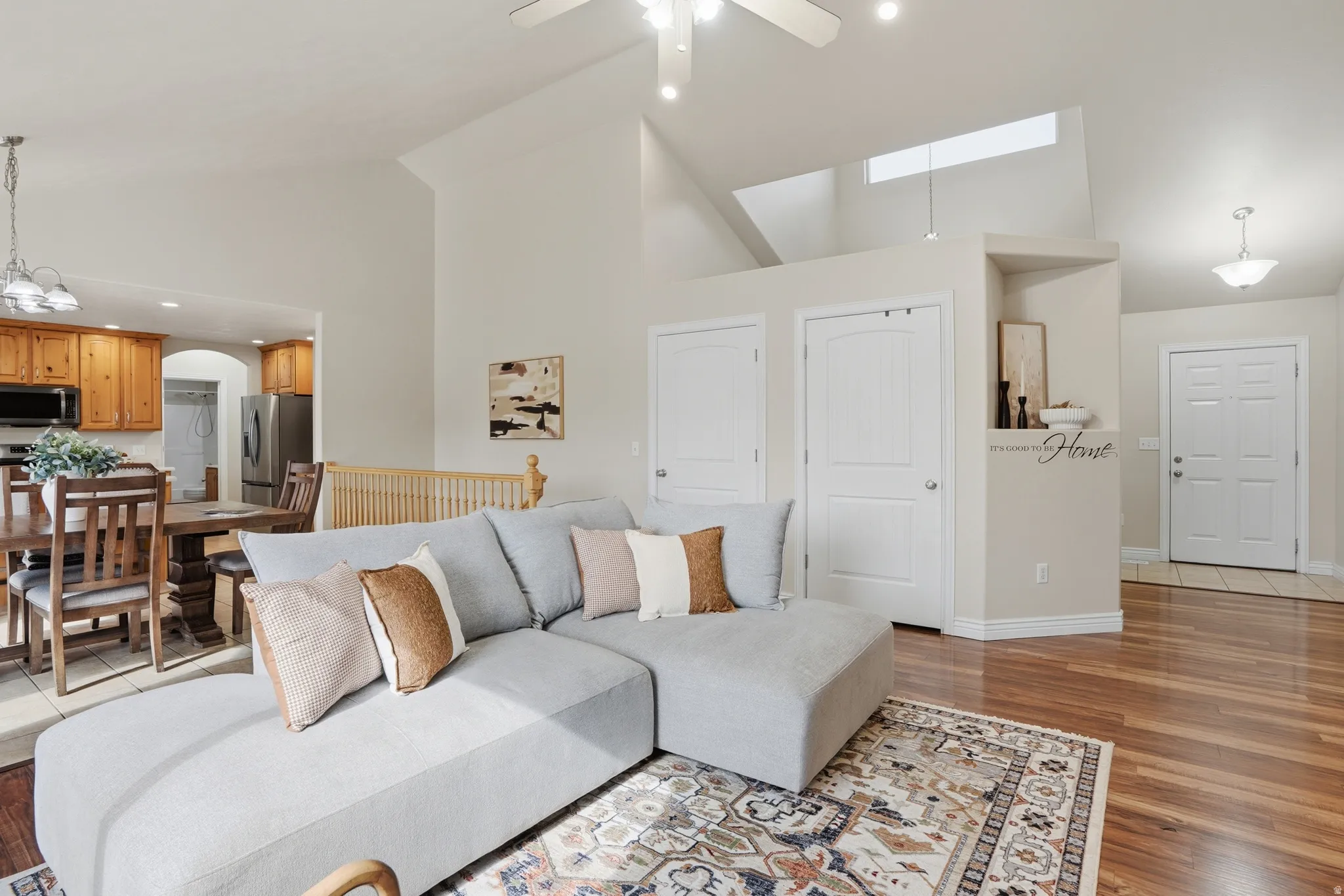 Expansive living area featuring vaulted ceilings with a ceiling fan, wood-finish flooring, and an open concept layout