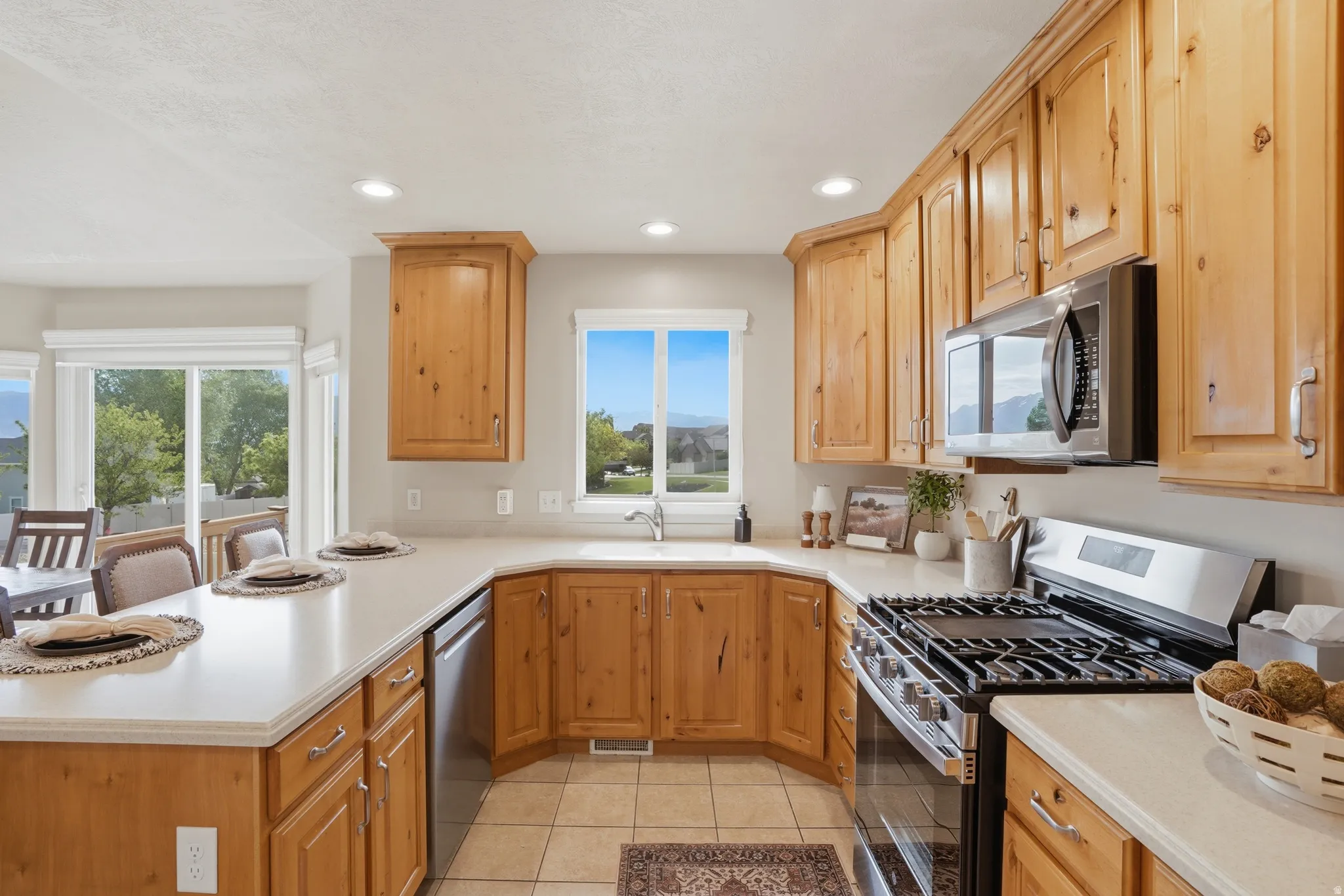 Kitchen featuring wood cabinetry, white countertops, stainless steel appliances, and a tile floor