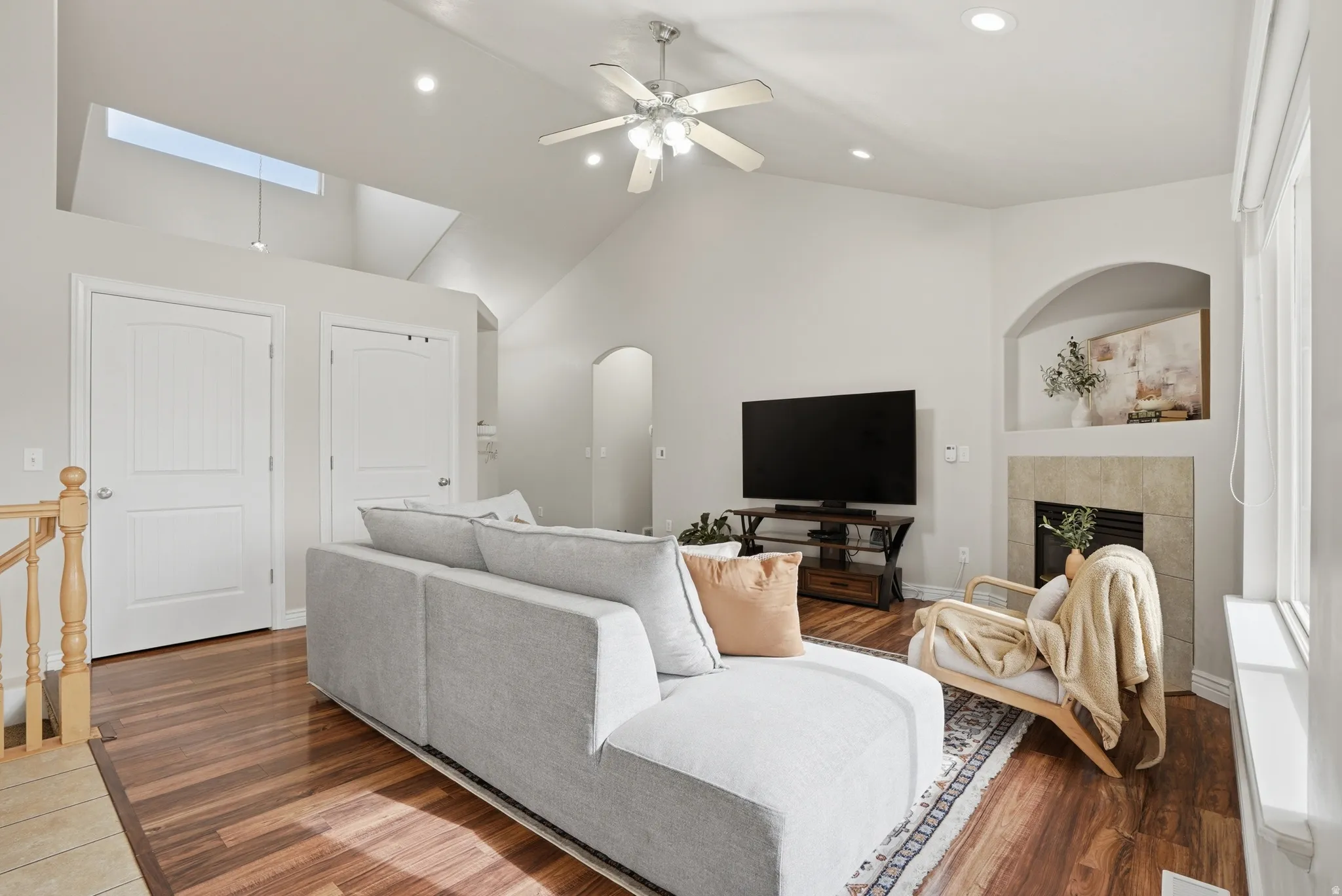 Spacious living area featuring vaulted ceilings, wood-finish flooring, recessed lighting, and a skylight