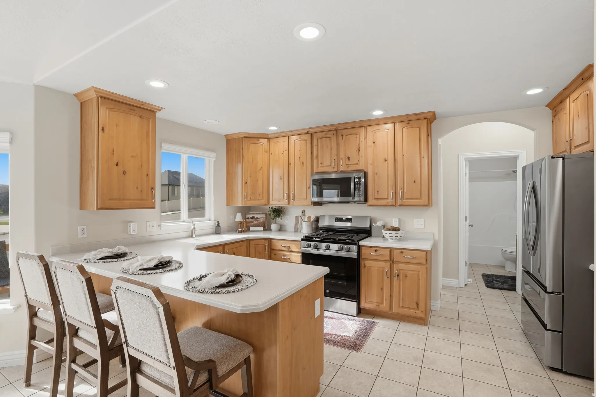 Spacious kitchen featuring natural wood cabinetry, light-toned countertops, and recessed lighting