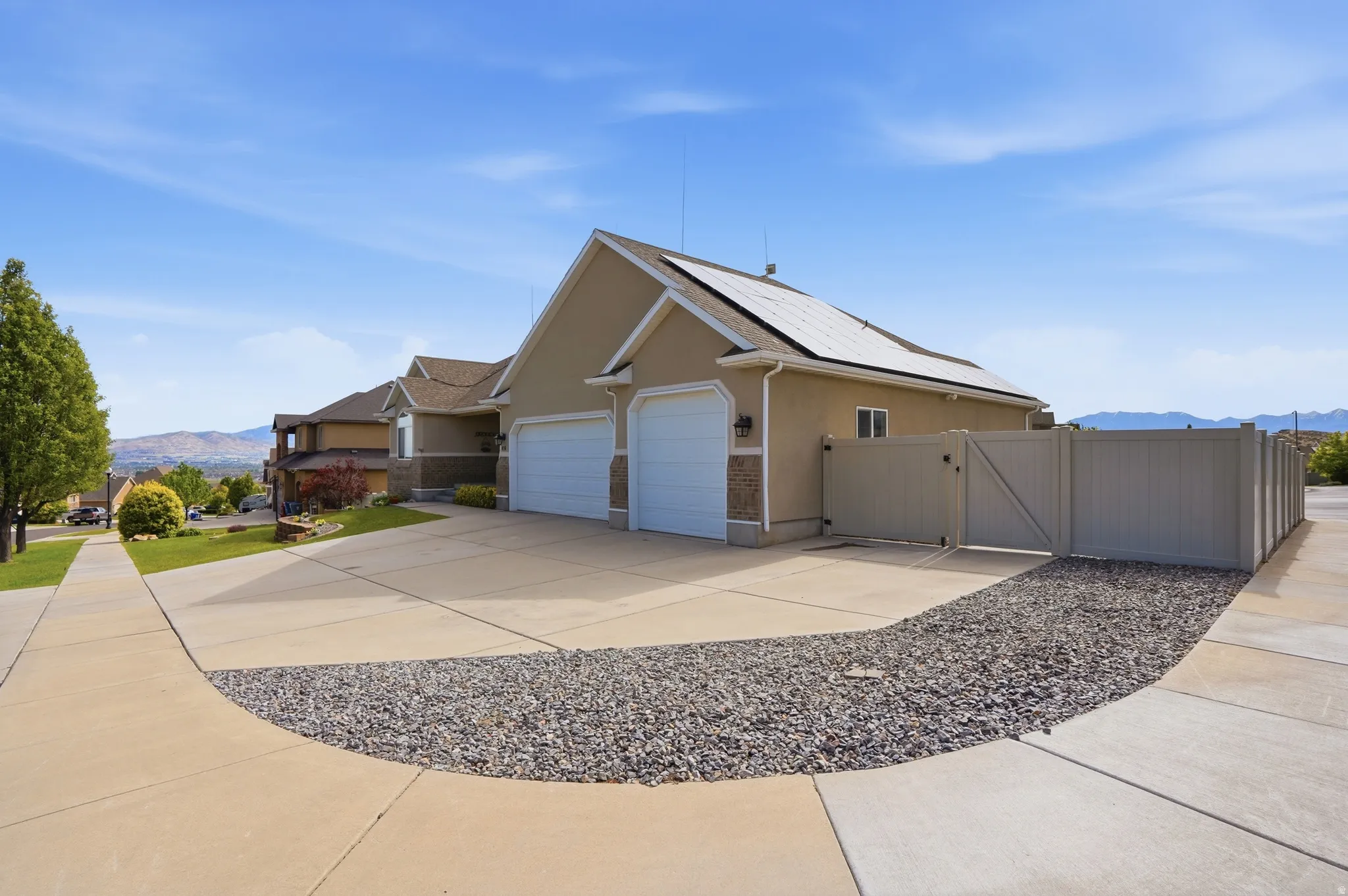 Stucco exterior residence featuring a two-car garage, solar panels, and a concrete driveway