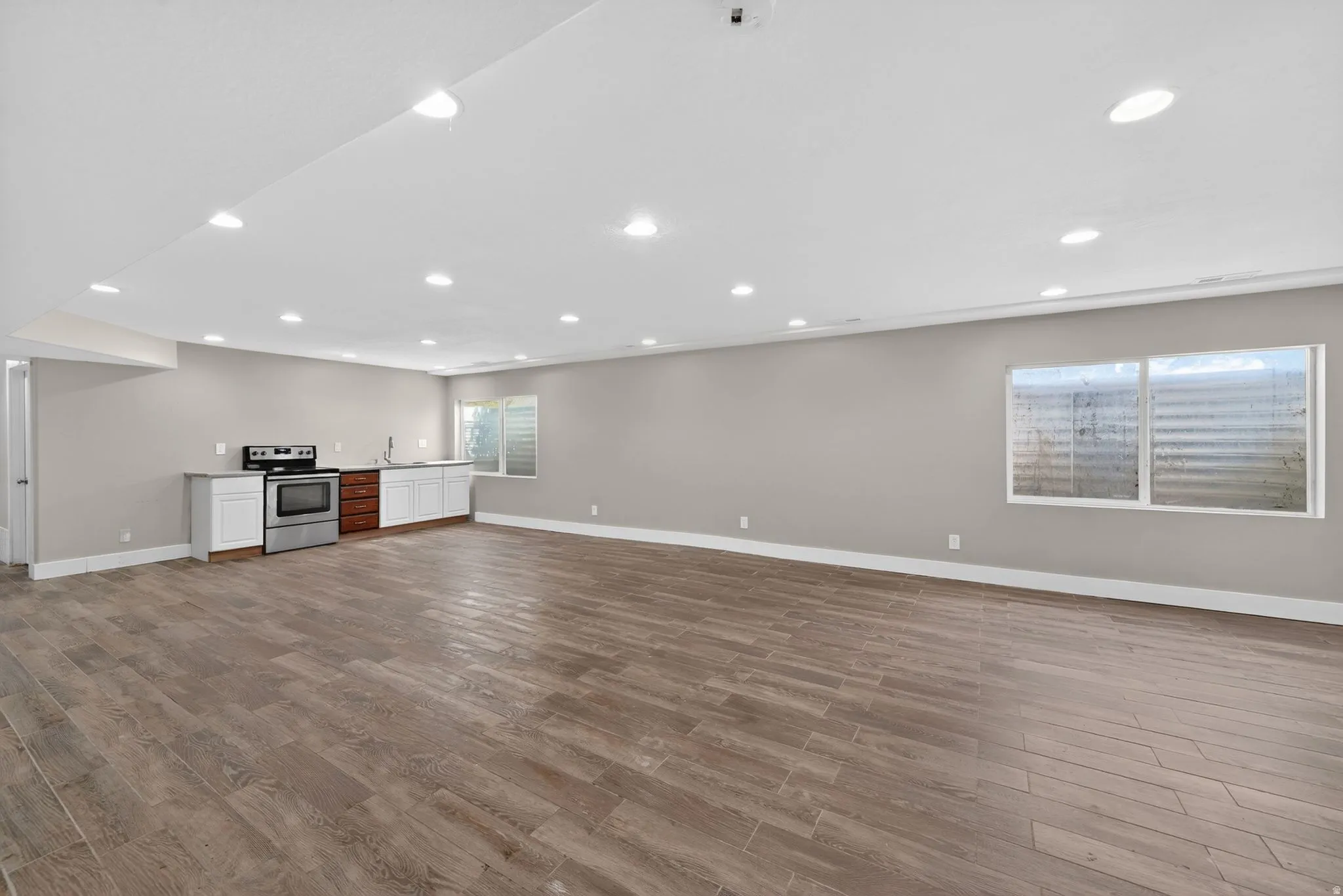 Expansive room featuring wood-finish flooring, recessed ceiling lighting, and neutral wall tones
