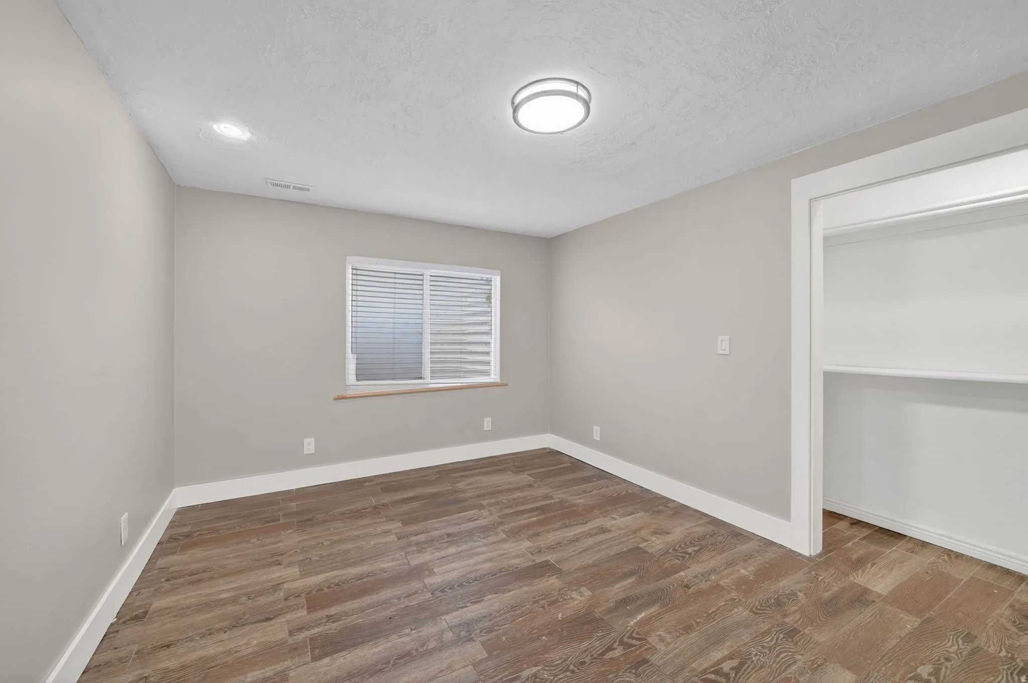 Room featuring wood-finish flooring, neutral wall paint, and white trim