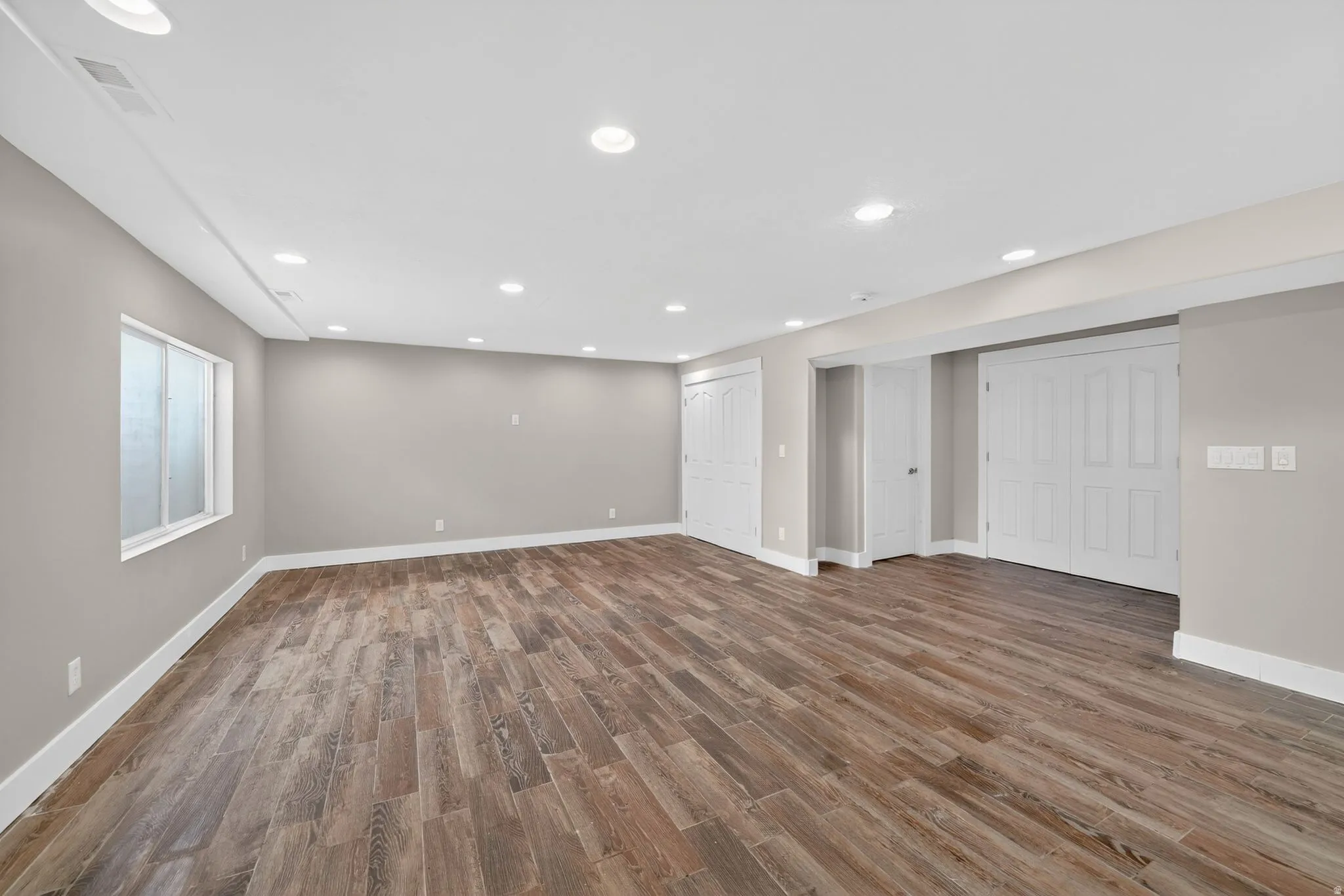 Spacious finished area featuring wood-finish flooring, recessed lighting, and light-toned wall paint