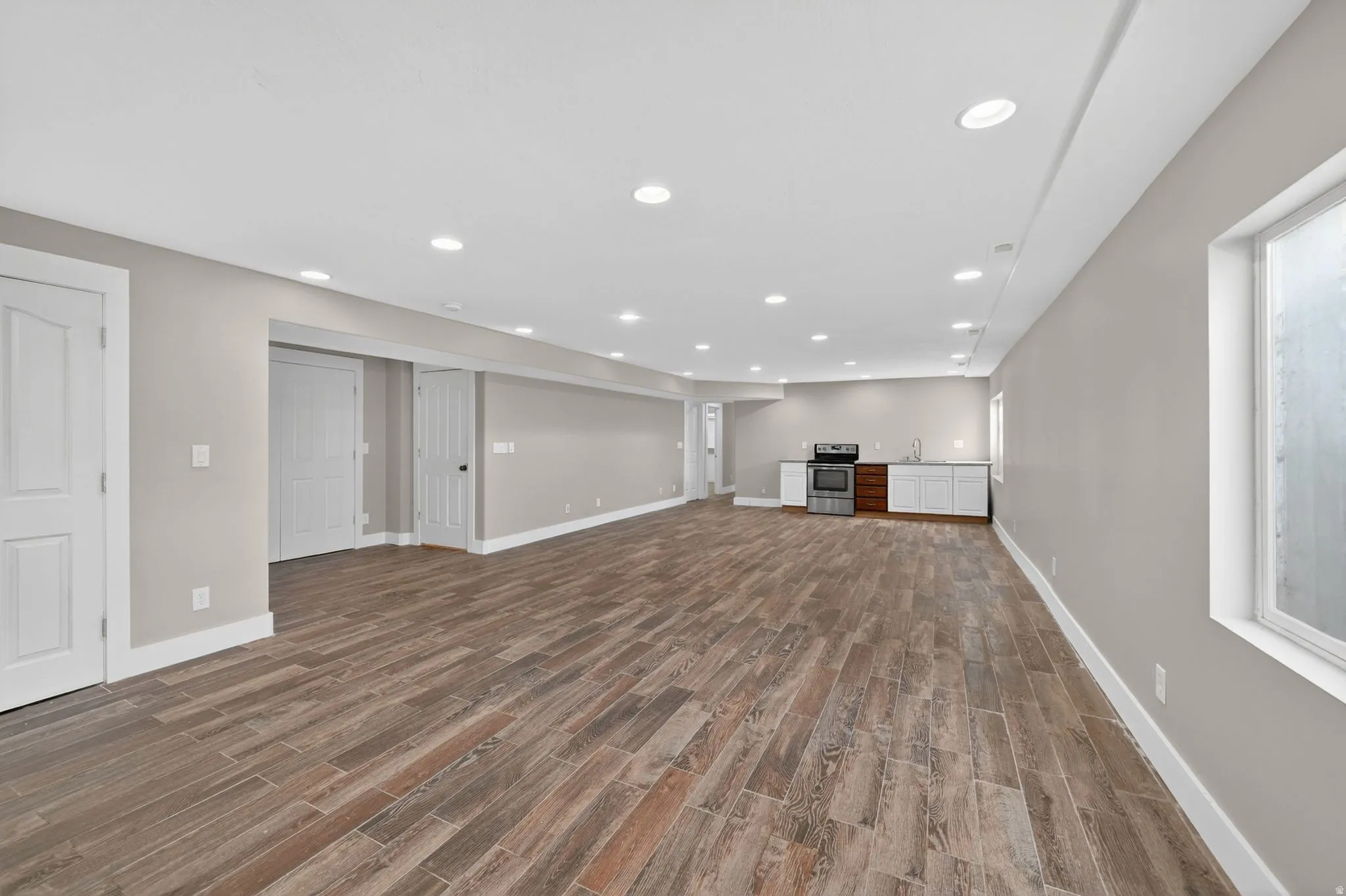 Spacious room featuring wood-finish flooring, recessed lighting, and light gray wall paint