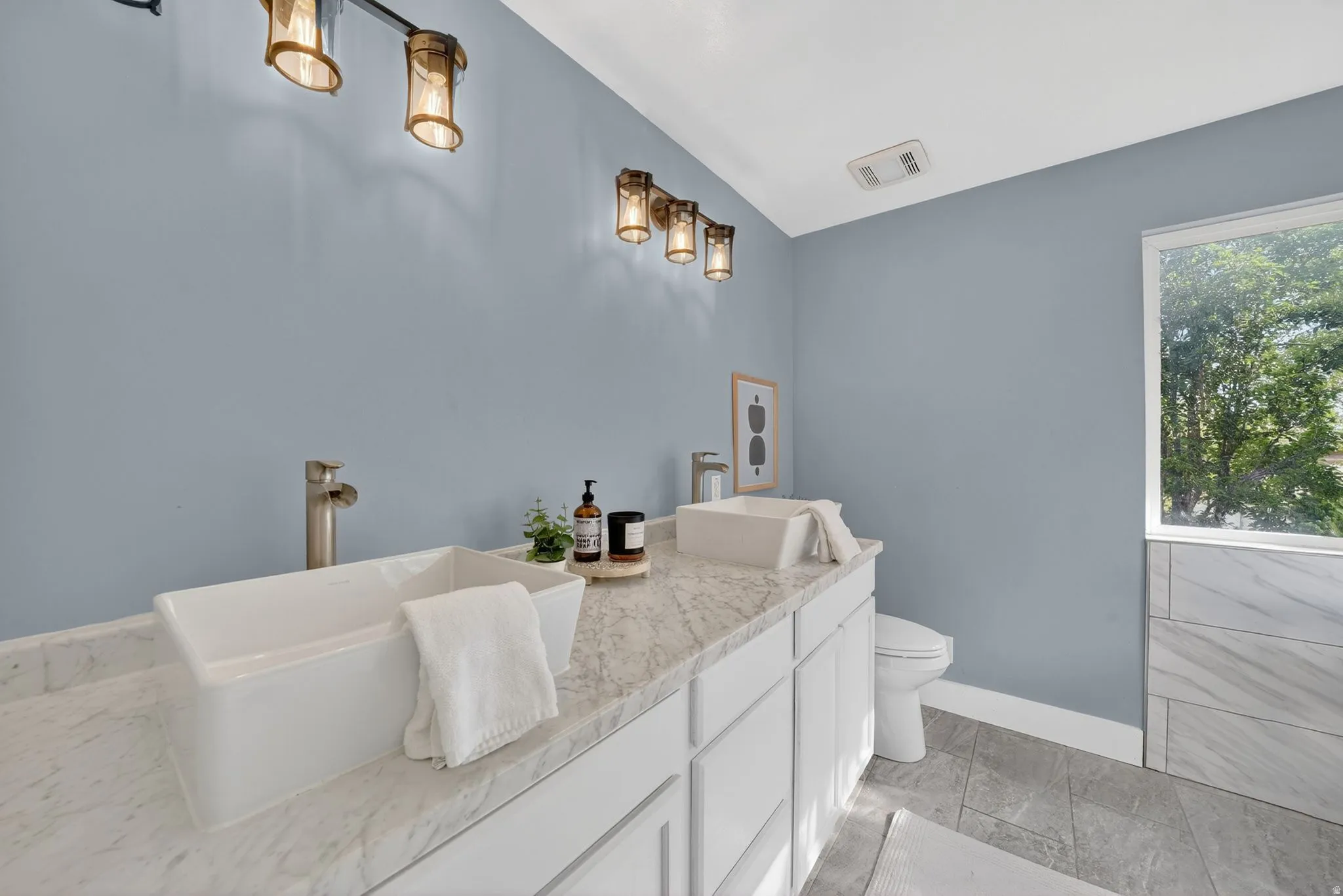 Dual vessel sinks set on a light-toned countertop with integrated cabinetry