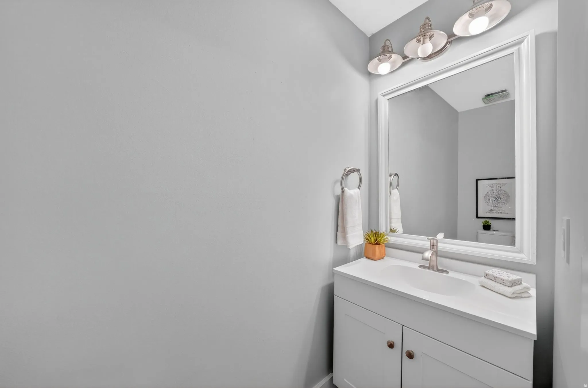 Single vanity with integrated sink, white countertop, and brushed nickel faucet