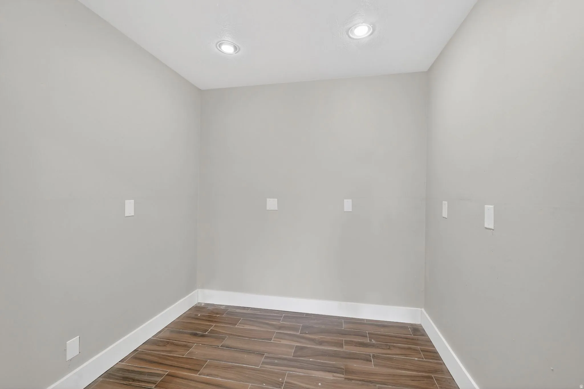 Room featuring wood-look tile flooring, white baseboards, light grey walls, and recessed ceiling lighting