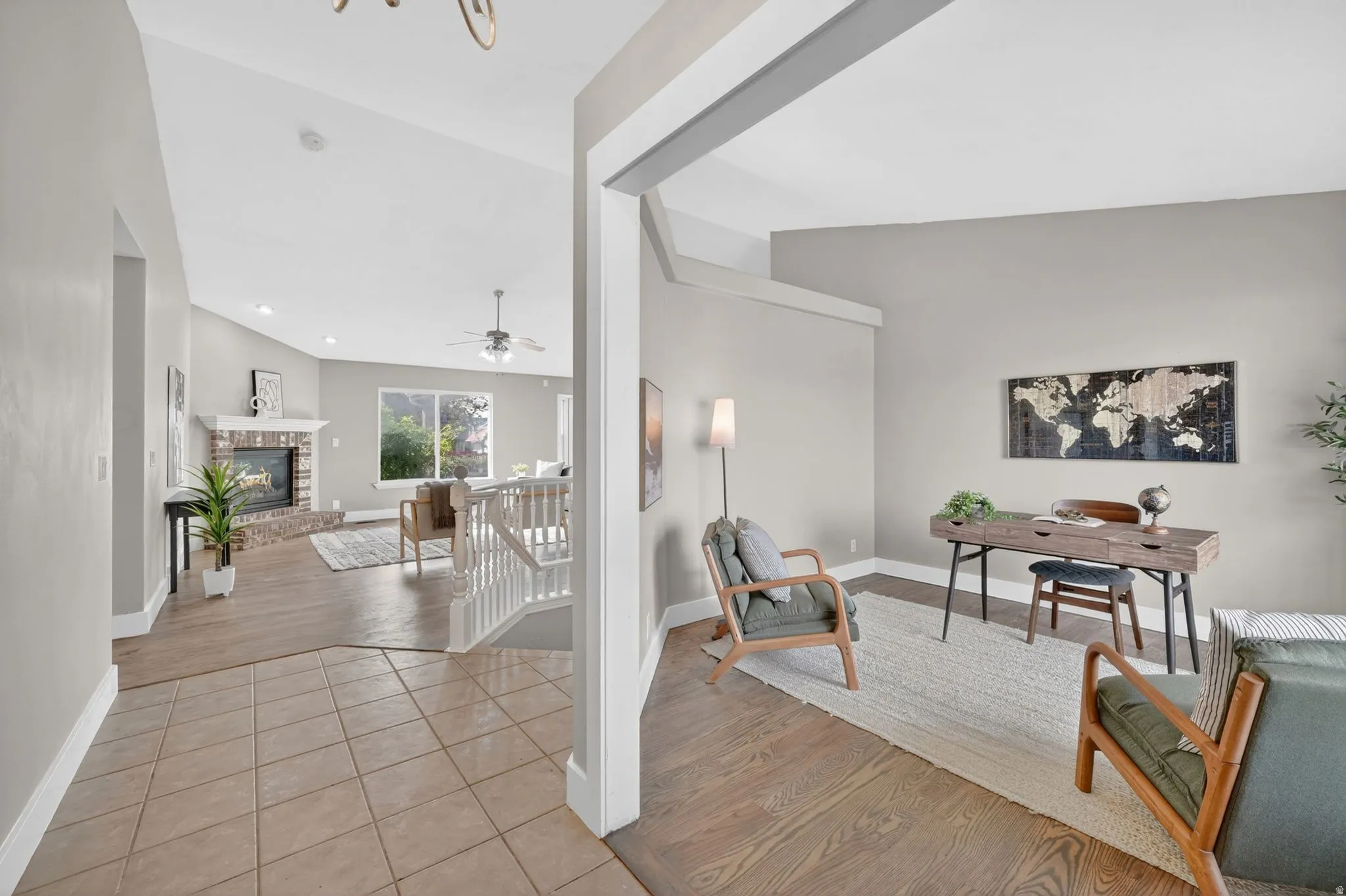 Tiled entry foyer opening to a living area with wood-finish flooring, a brick fireplace, and a large window