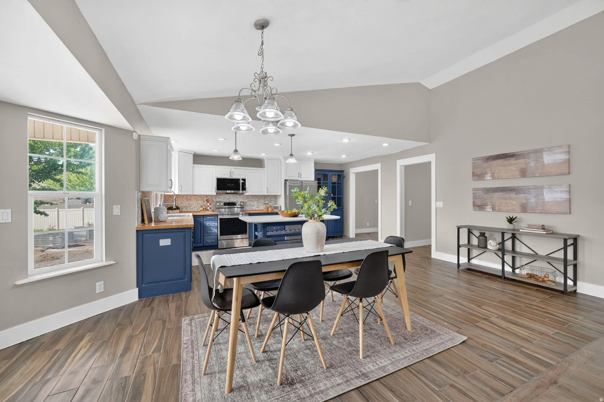 Open-concept living space featuring wood-finish flooring, vaulted ceilings, and a neutral color palette