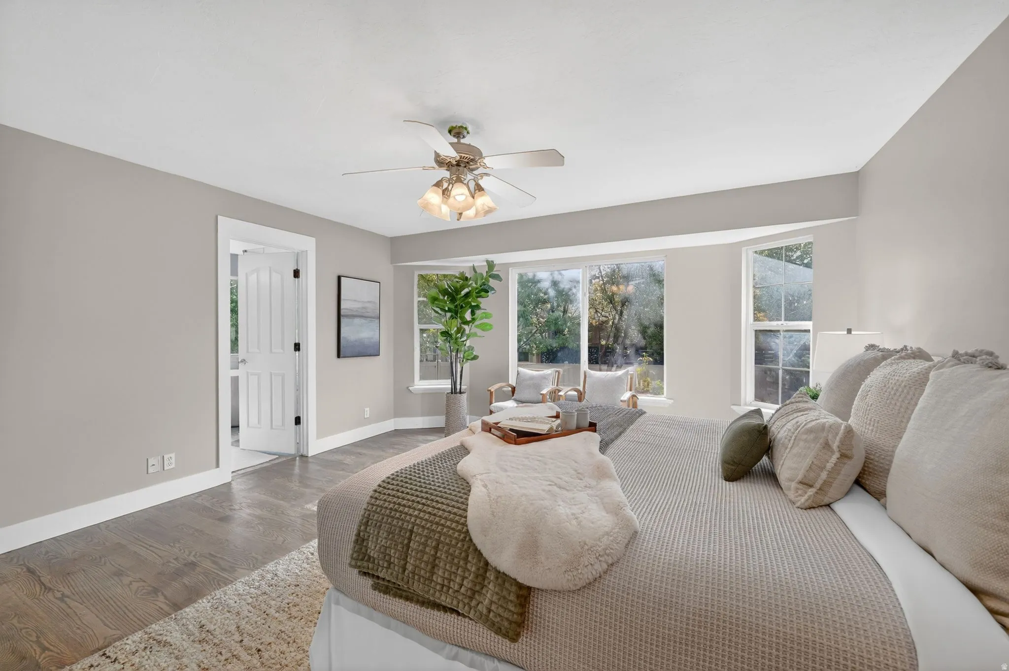 Spacious room featuring wood-finish flooring, a ceiling fan with integrated lighting, and a bay window configuration