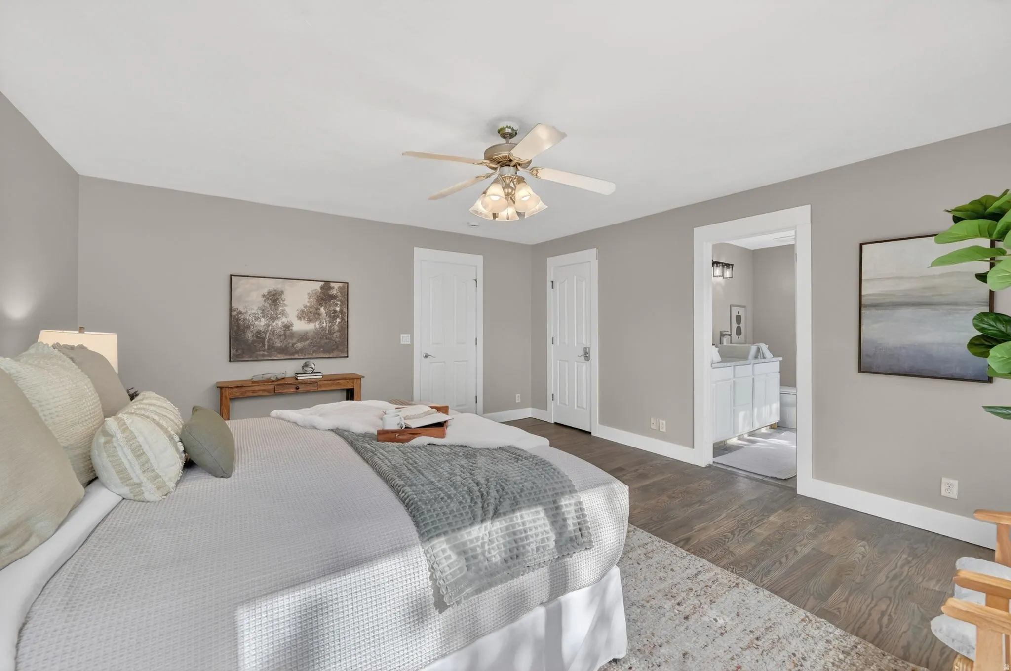 Spacious room featuring wood-finish flooring, a ceiling fan, and light gray walls