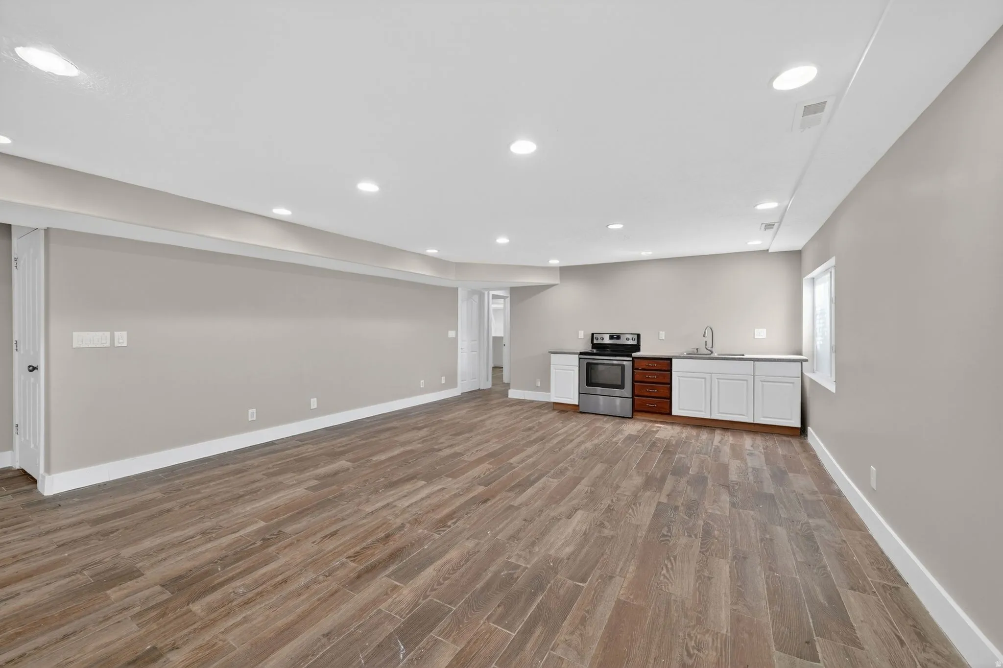 Spacious open-concept room featuring wood-finish flooring, recessed lighting, and neutral wall tones