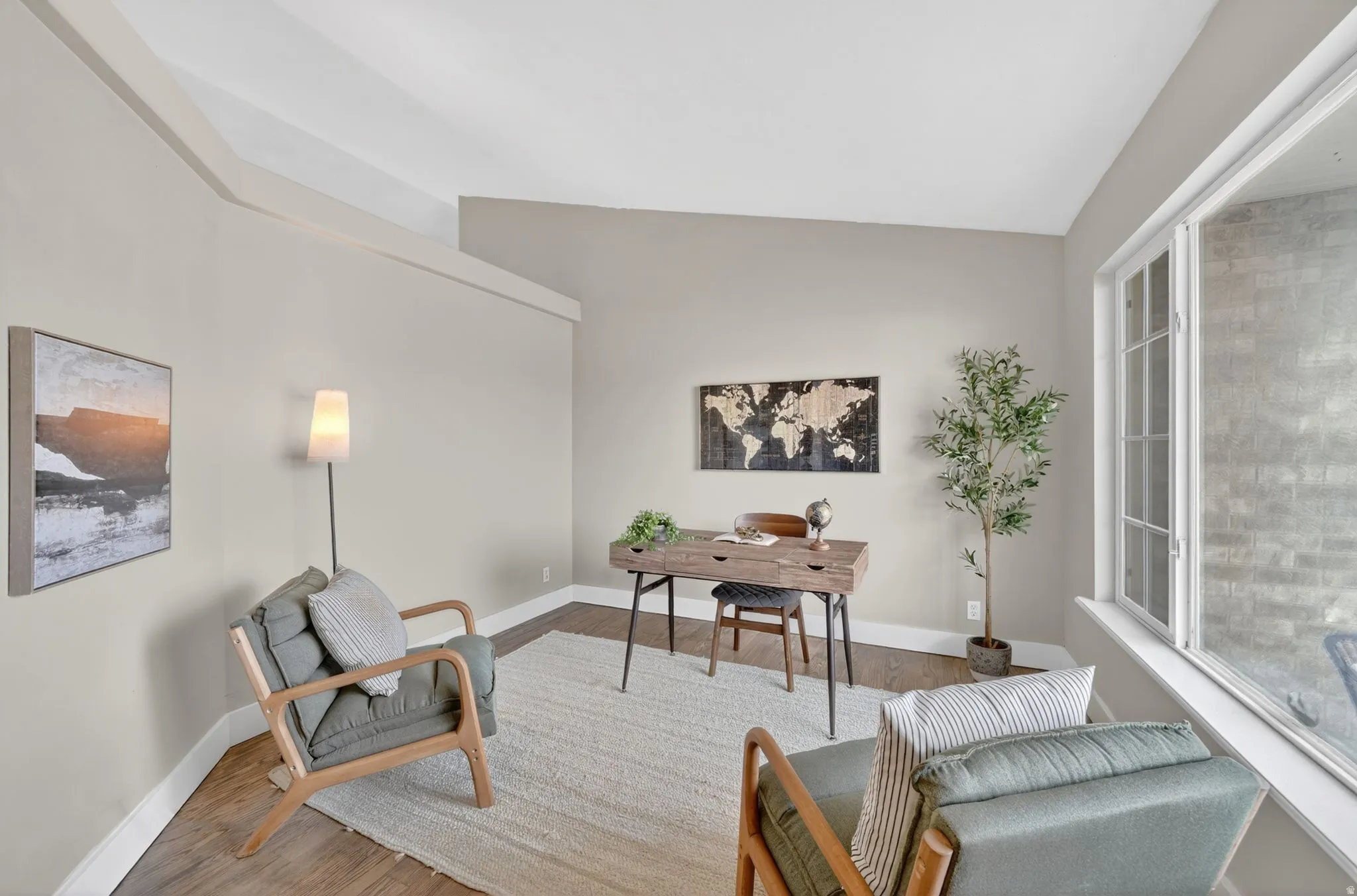 Bright interior space featuring wood-finish flooring, a large multi-pane window, and neutral wall tones