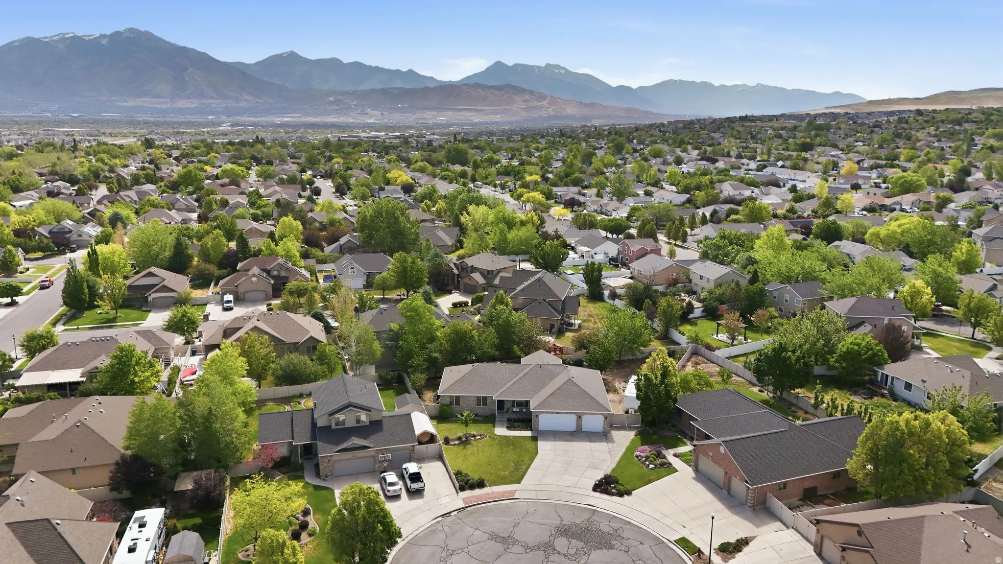 Aerial perspective of a residential community with mature trees and mountain backdrop