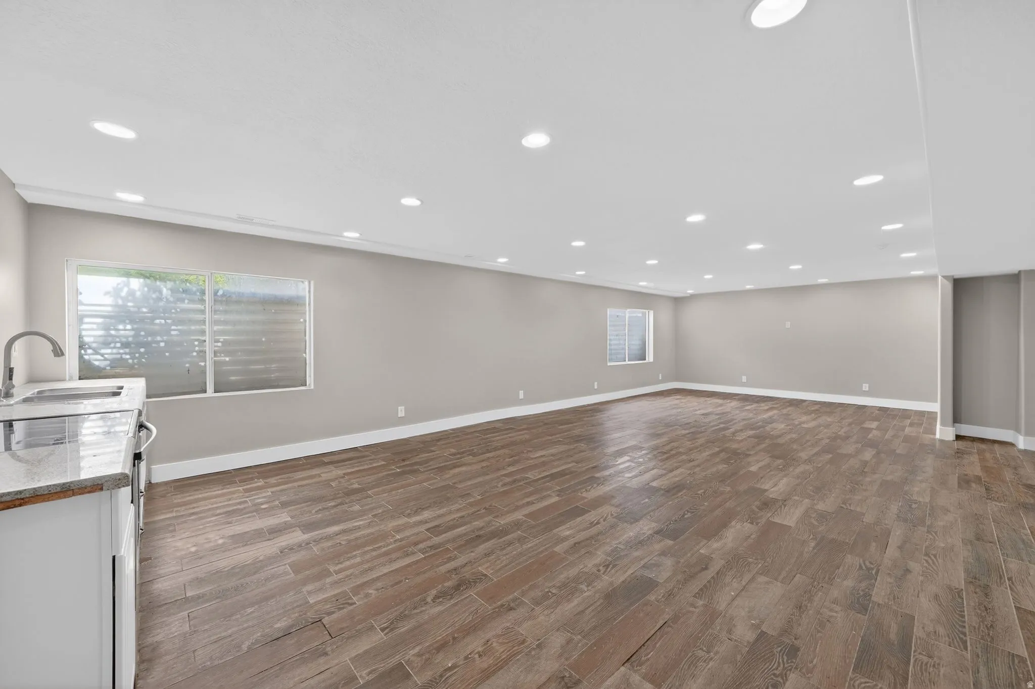 Spacious room featuring wood-finish plank flooring, recessed lighting, and light gray walls