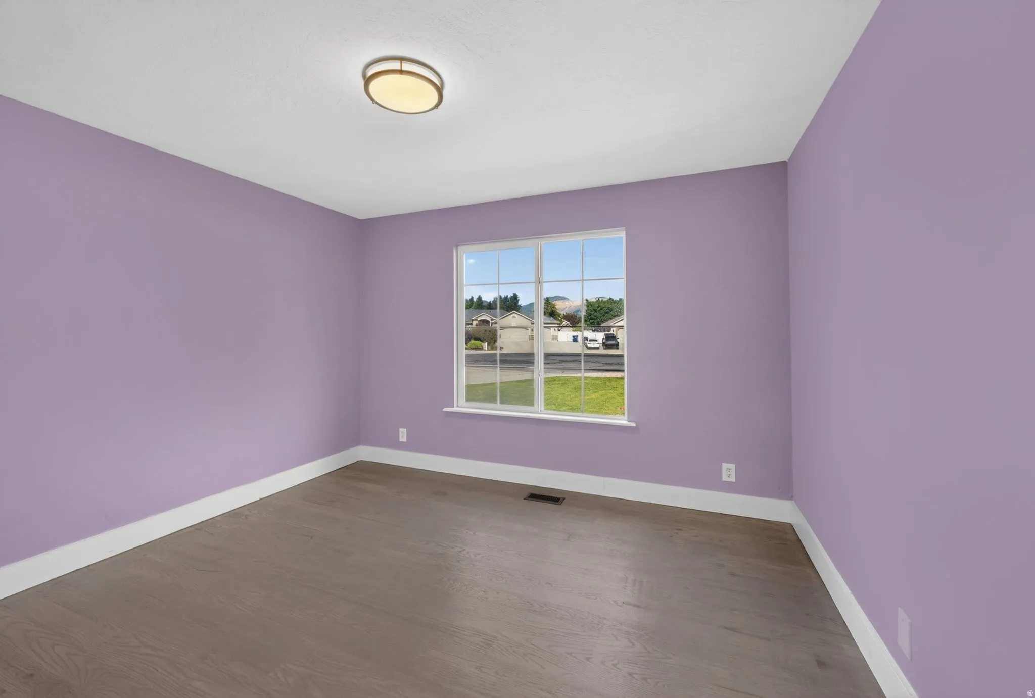 Bright room featuring wood-finish flooring, white baseboards, and a large multi-pane window