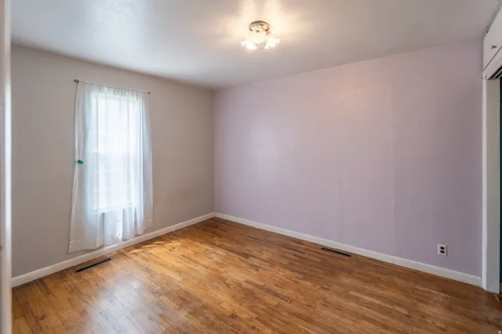 Interior room featuring wood-finish flooring, a double-hung window, and a flush-mount ceiling light fixture