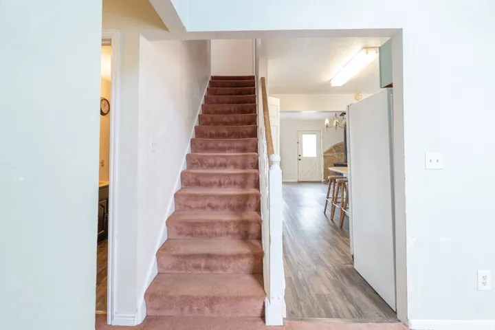 Carpeted staircase with white balusters leading to an upper level