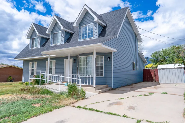 Blue siding exterior with multiple dormers, covered front porch, and a white railing ramp