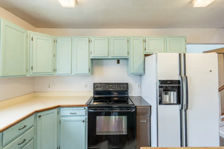 Kitchen featuring light blue cabinetry, white countertops, and a black electric range