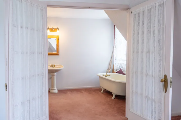 Bathroom featuring a freestanding clawfoot tub, pedestal sink, and a wood-framed mirror