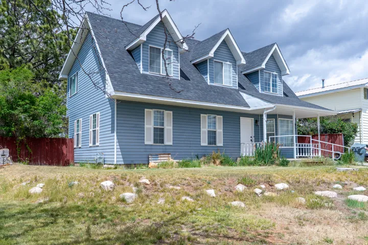 Two-story residence featuring blue horizontal siding, a dark shingle roof, and multiple dormer windows