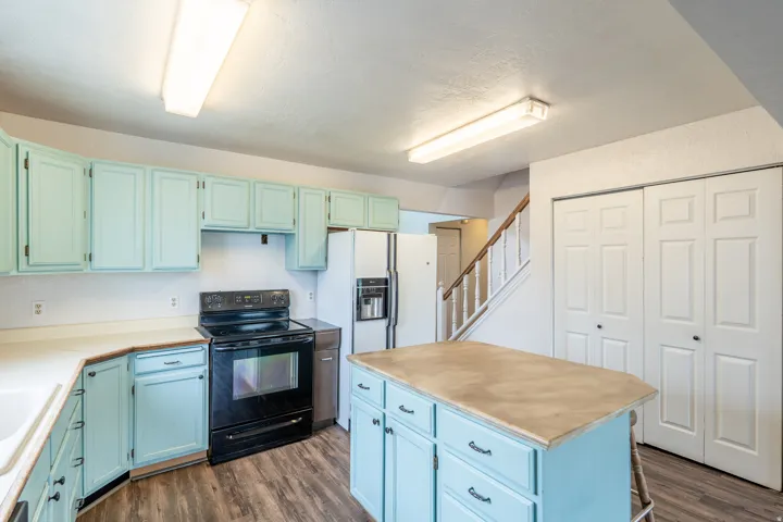 Kitchen featuring light blue cabinetry and a coordinating island with an expansive countertop