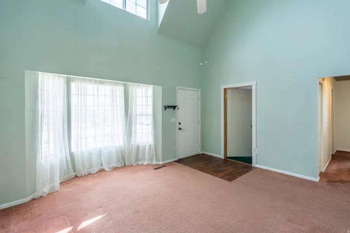 Vaulted ceiling interior with an upper-level window and a large bay window