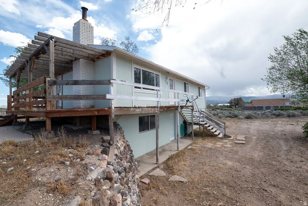 Two-story exterior with light blue siding, featuring an expansive wood deck with a pergola